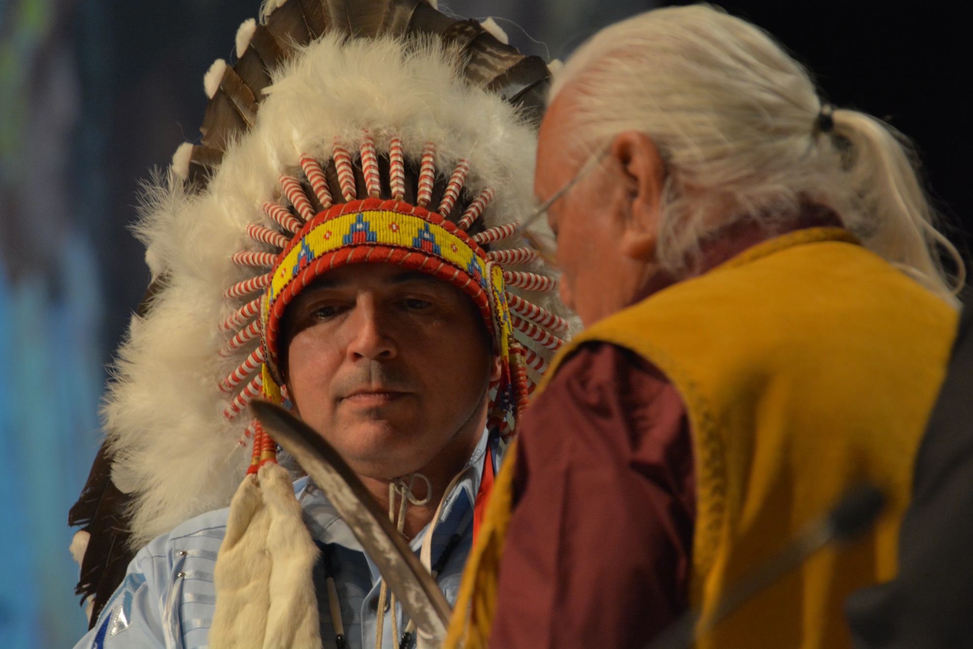 Perry Bellegarde in a feathered headdress, eyes lowered, as Elder Elmer Courchene swears him in as National Chief, Winnipeg, 2014